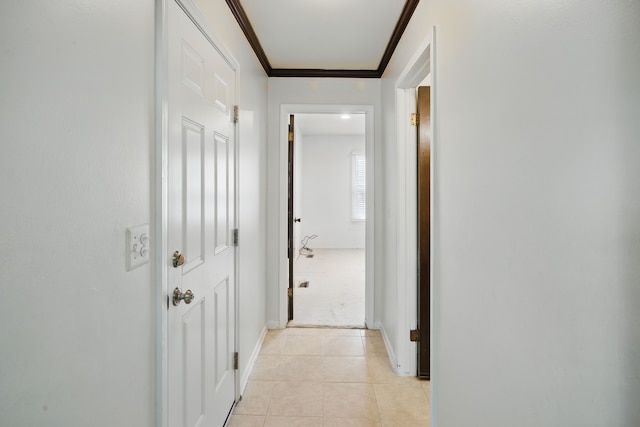 hallway with light tile patterned floors, ornamental molding, and baseboards