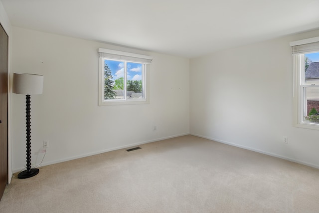 spare room with light carpet and baseboards