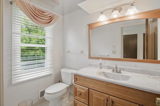bathroom with plenty of natural light, toilet, vanity, and tile patterned floors