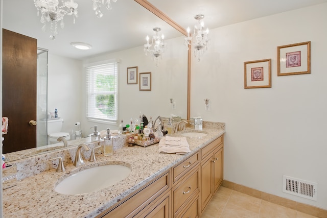 bathroom featuring a chandelier, toilet, tile patterned flooring, double vanity, and baseboards