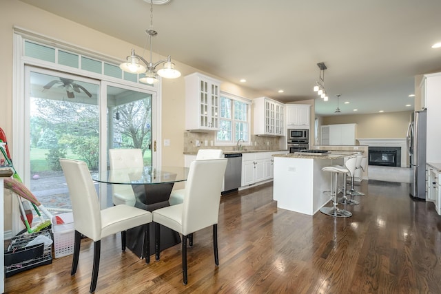 7294 Mackenzie Ln, Portage, MI 49024 - kitchen featuring appliances with stainless steel finishes, a kitchen island, dark wood-style floors, white cabinetry, and a breakfast bar area