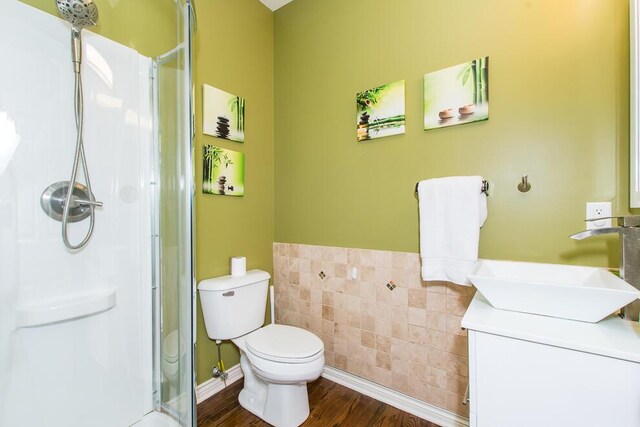 7294 Mackenzie Ln, Portage, MI 49024 - bathroom with a stall shower, toilet, wood finished floors, vanity, and tile walls