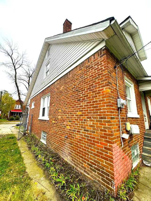 view of property exterior with brick siding and a chimney