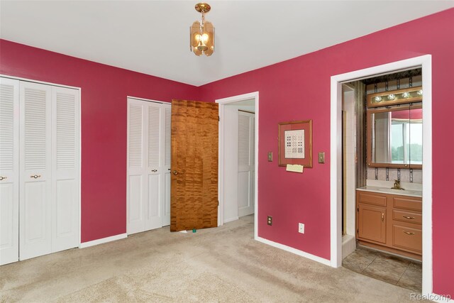 2982 Shawnee Ln, Waterford, MI 48329 - unfurnished bedroom with light carpet, multiple closets, baseboards, and a sink