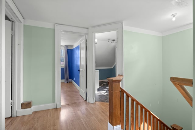 hall with an upstairs landing, wood finished floors, and baseboards