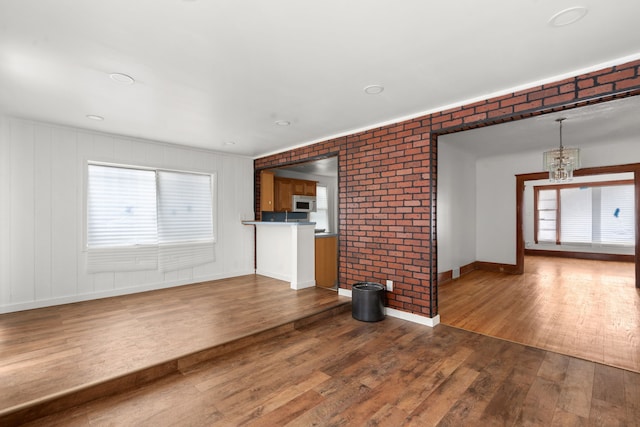 5370 Seebaldt St, Detroit, MI 48204 - unfurnished living room with wood finished floors, a chandelier, baseboards, and brick wall