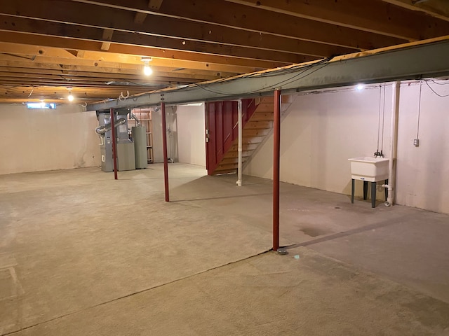 unfinished basement featuring stairway, water heater, and a sink