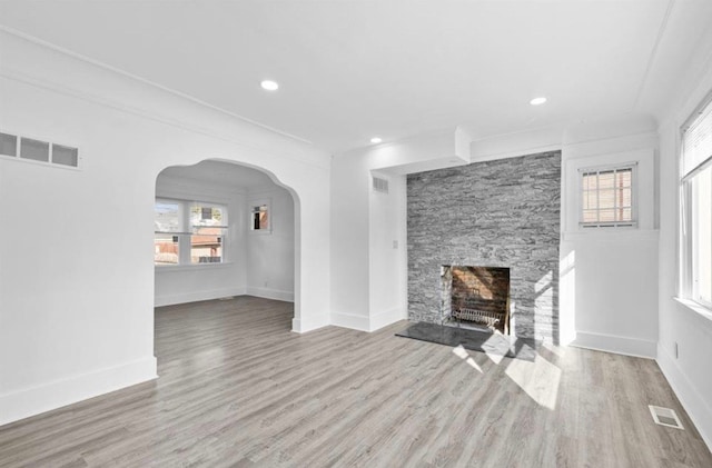 7305 Appoline St, Dearborn, MI 48126 - unfurnished living room featuring wood finished floors, arched walkways, baseboards, a stone fireplace, and recessed lighting