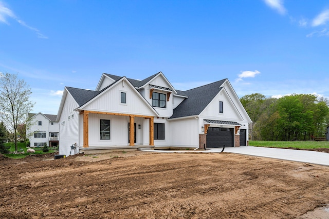 modern farmhouse featuring covered porch, driveway, and a shingled roof