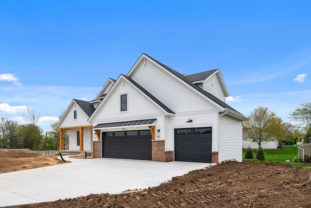 modern farmhouse style home with driveway, a standing seam roof, brick siding, and an attached garage