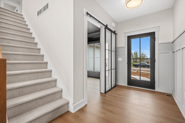 doorway with a barn door, stairway, and wood finished floors