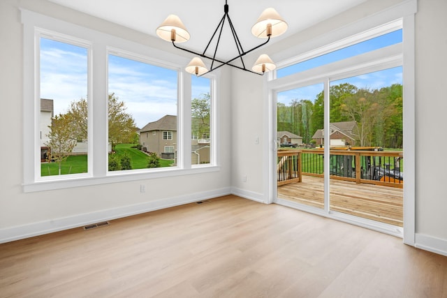 unfurnished dining area featuring wood finished floors, a chandelier, and baseboards