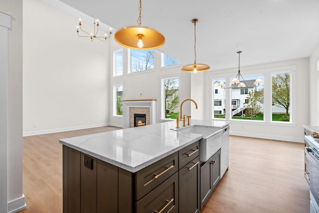 kitchen with a sink, a chandelier, light wood-type flooring, dishwasher, and pendant lighting