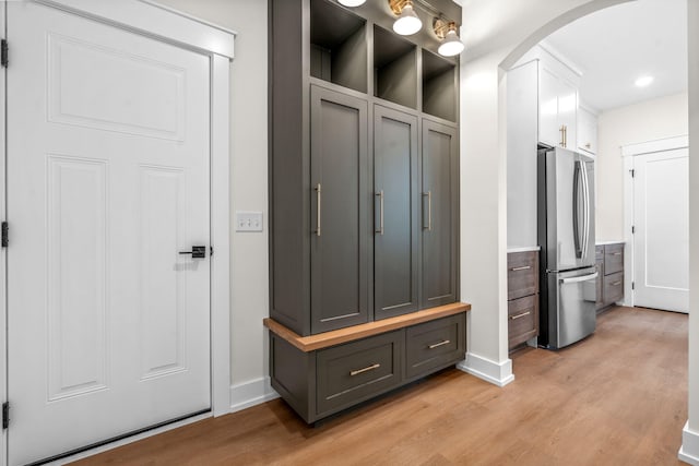 mudroom featuring arched walkways, light wood-style flooring, baseboards, and recessed lighting