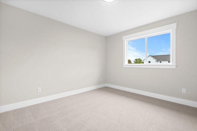 carpeted empty room featuring baseboards