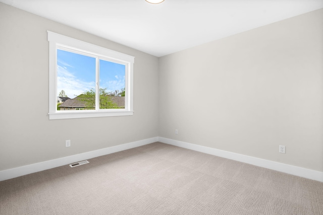 spare room featuring light colored carpet and baseboards