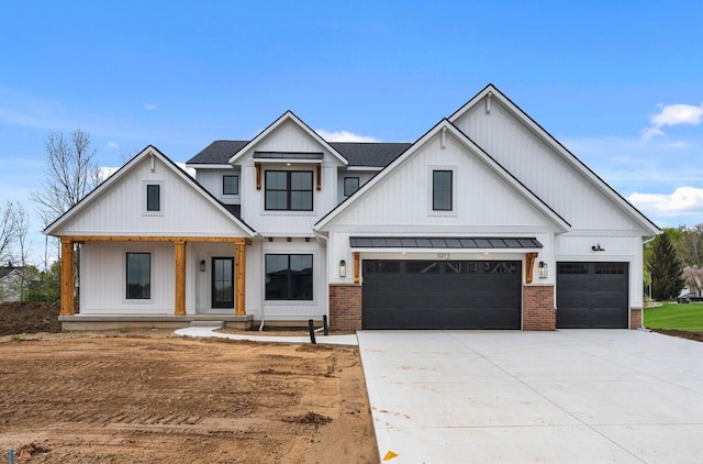 modern farmhouse style home with a standing seam roof, driveway, covered porch, metal roof, and a garage