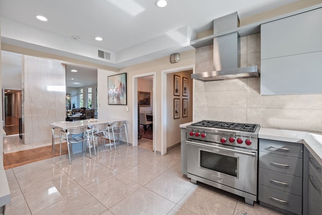 5280 Brookdale Rd, Bloomfield Hills, MI 48304 - kitchen featuring luxury stove, wall chimney exhaust hood, gray cabinets, light countertops, and decorative backsplash