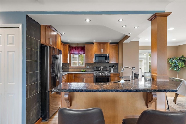 23142 Port St, Saint Clair Shores, MI 48082 - kitchen with appliances with stainless steel finishes, a sink, a kitchen bar, brown cabinets, and tasteful backsplash