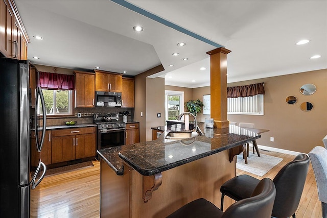 23142 Port St, Saint Clair Shores, MI 48082 - kitchen with appliances with stainless steel finishes, a sink, light wood-style floors, a breakfast bar, and brown cabinetry