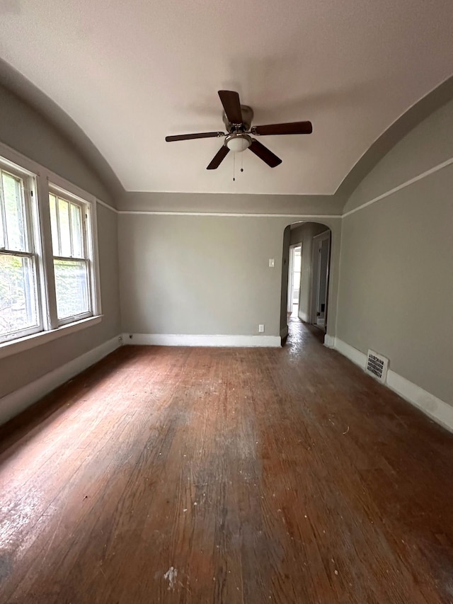 empty room featuring vaulted ceiling, wood-type flooring, arched walkways, ceiling fan, and healthy amount of natural light