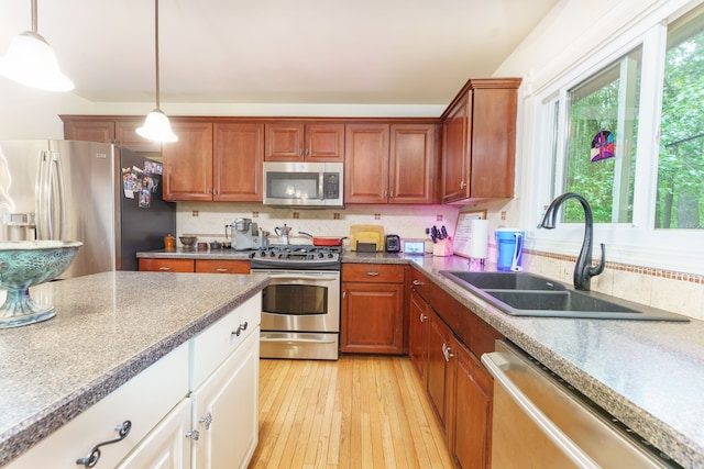 1418 Trailside Blvd, Wixom, MI 48393 - kitchen featuring stainless steel appliances, a sink, pendant lighting, light wood-style floors, and brown cabinetry