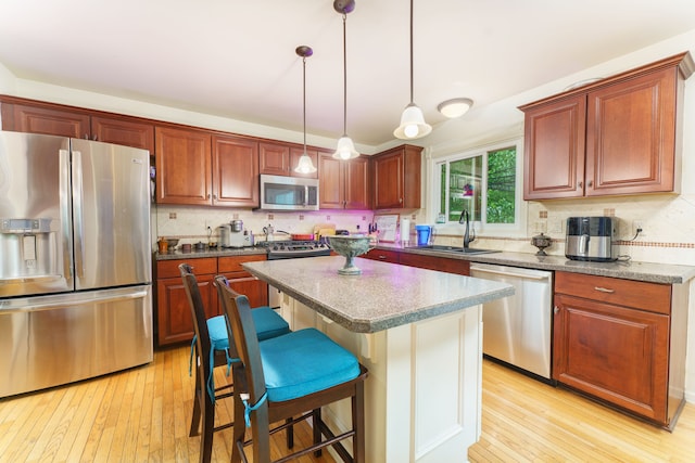 1418 Trailside Blvd, Wixom, MI 48393 - kitchen with stainless steel appliances, a sink, light wood-style floors, and a breakfast bar