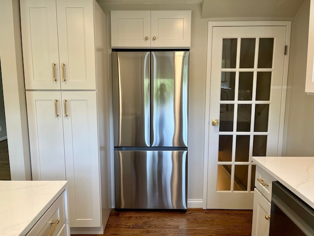 kitchen with freestanding refrigerator, dark wood-style floors, white cabinets, dishwashing machine, and light stone counters