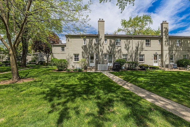 back of house featuring a lawn, a chimney, and cooling unit