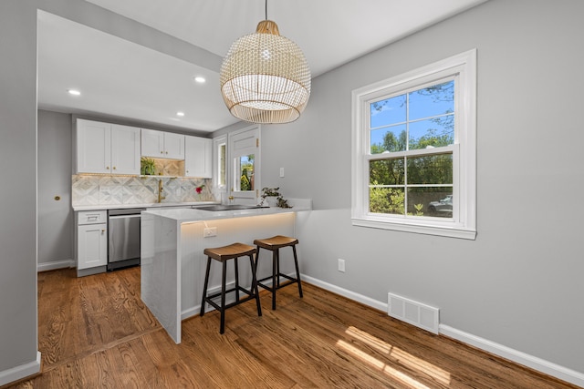 kitchen featuring stainless steel dishwasher, white cabinets, healthy amount of natural light, wood finished floors, and recessed lighting