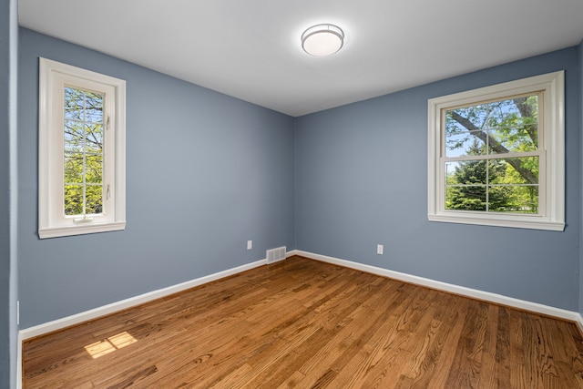 unfurnished room with plenty of natural light, baseboards, and wood finished floors