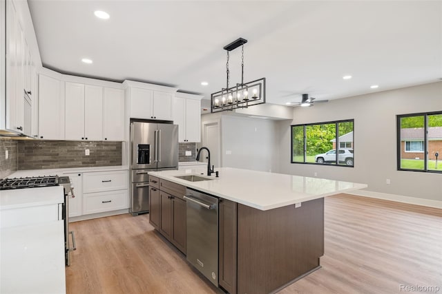 7598 Lake Park Rd, Ira, MI 48023 - kitchen with appliances with stainless steel finishes, a sink, light wood finished floors, light countertops, and backsplash