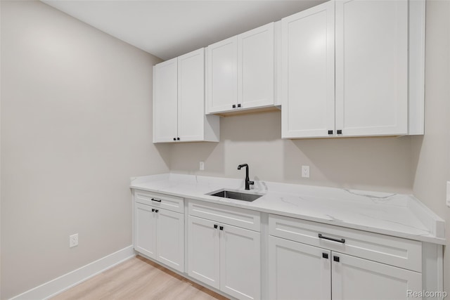 7598 Lake Park Rd, Ira, MI 48023 - kitchen with a sink, white cabinetry, light wood-type flooring, baseboards, and light stone countertops