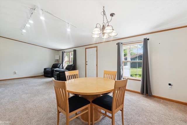 dining room featuring rail lighting, light colored carpet, baseboards, a chandelier, and ornamental molding