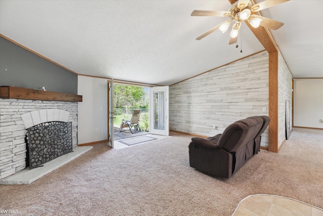 living room with vaulted ceiling, carpet flooring, ceiling fan, a fireplace with raised hearth, and baseboards