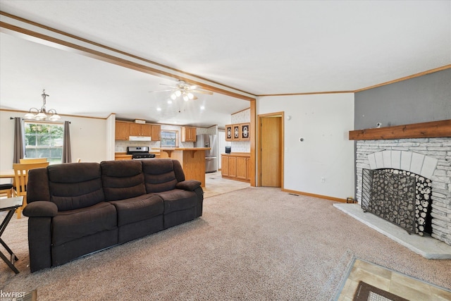 living area featuring light colored carpet, a fireplace with raised hearth, ceiling fan, baseboards, and ornamental molding