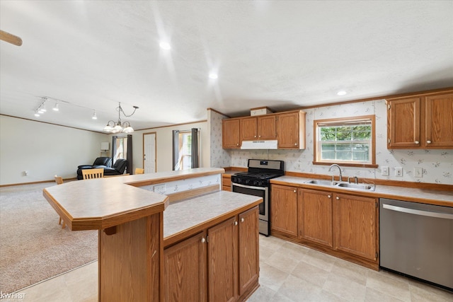 kitchen featuring appliances with stainless steel finishes, a sink, under cabinet range hood, a kitchen island, and light countertops