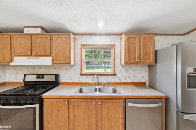 kitchen featuring stainless steel appliances, a sink, wallpapered walls, under cabinet range hood, and light countertops