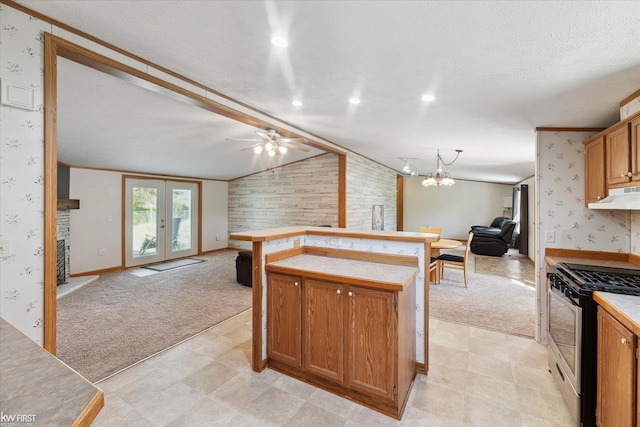 kitchen with open floor plan, gas range, under cabinet range hood, wallpapered walls, and light carpet