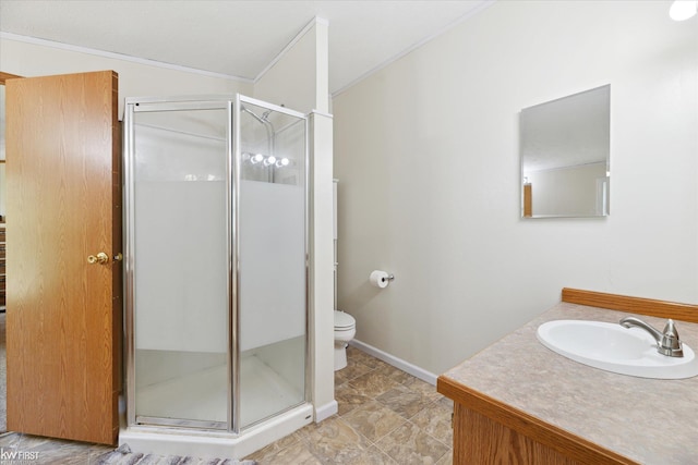 bathroom with a shower stall, crown molding, toilet, vanity, and baseboards