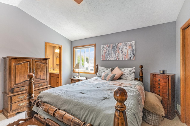 bedroom featuring light colored carpet, vaulted ceiling, a textured ceiling, and ensuite bathroom