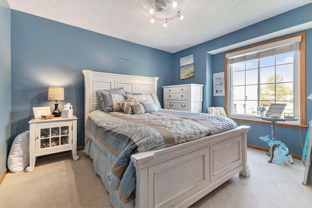 bedroom featuring light carpet, baseboards, and a textured ceiling