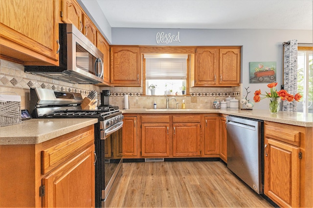 kitchen with appliances with stainless steel finishes, a sink, plenty of natural light, and light countertops