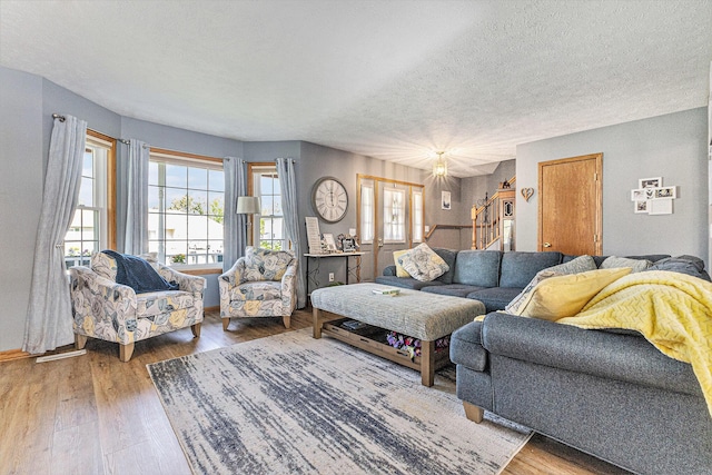 living room with a textured ceiling, plenty of natural light, wood finished floors, and baseboards
