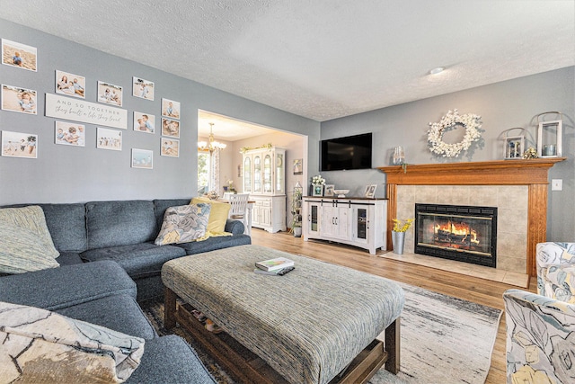 living area with wood finished floors, a chandelier, a textured ceiling, and a fireplace