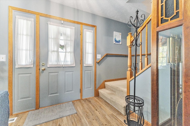 foyer featuring stairway, wood finished floors, a textured ceiling, and baseboards