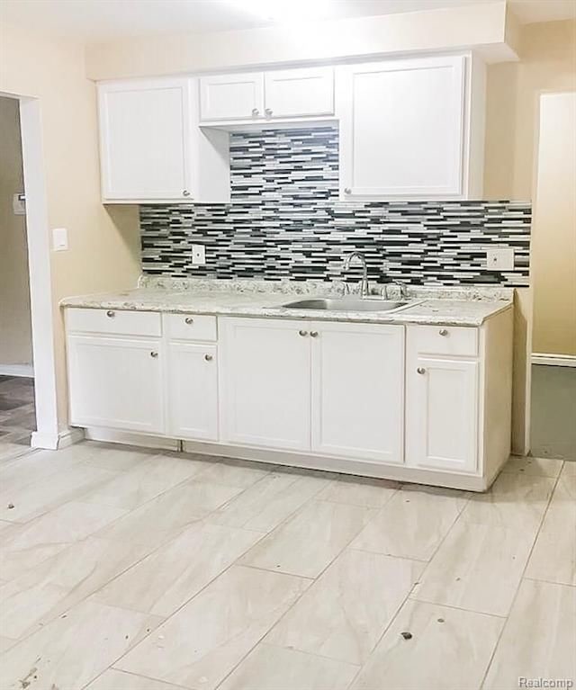 8090 Robson St, Detroit, MI 48228 - kitchen featuring a sink, white cabinetry, backsplash, and light stone countertops
