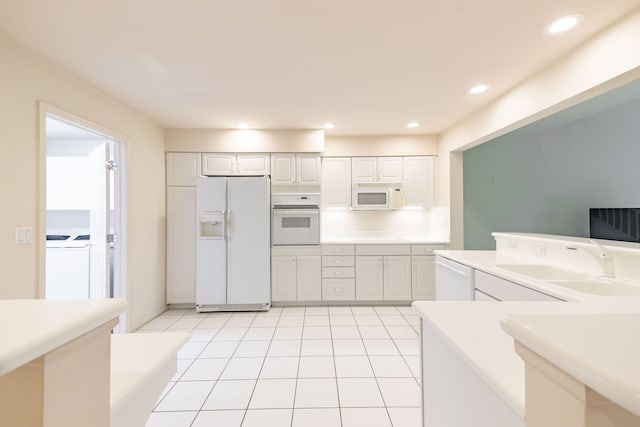 kitchen featuring white appliances, washer and dryer, a sink, white cabinets, and recessed lighting
