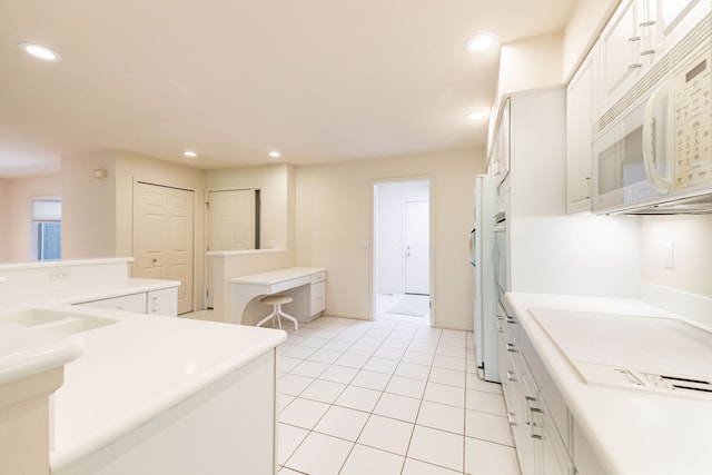 kitchen with white microwave, a sink, recessed lighting, white cabinetry, and light tile patterned floors