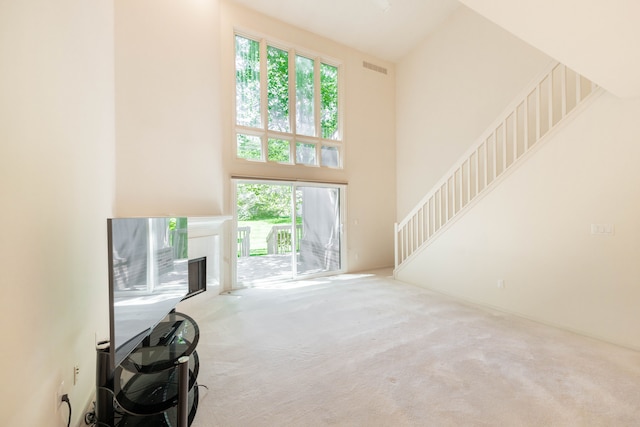 unfurnished living room featuring carpet floors, a high ceiling, and a premium fireplace
